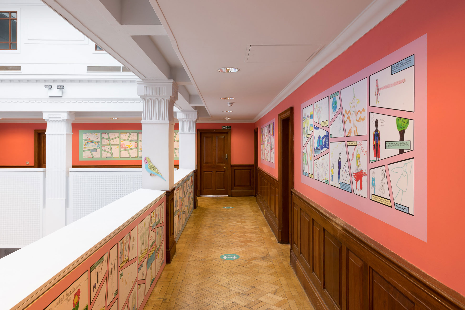 Coral walls feature comic book strips on large posters, showing the drawings submitted by Leeds locals for our Superheroes of Leeds exhibition