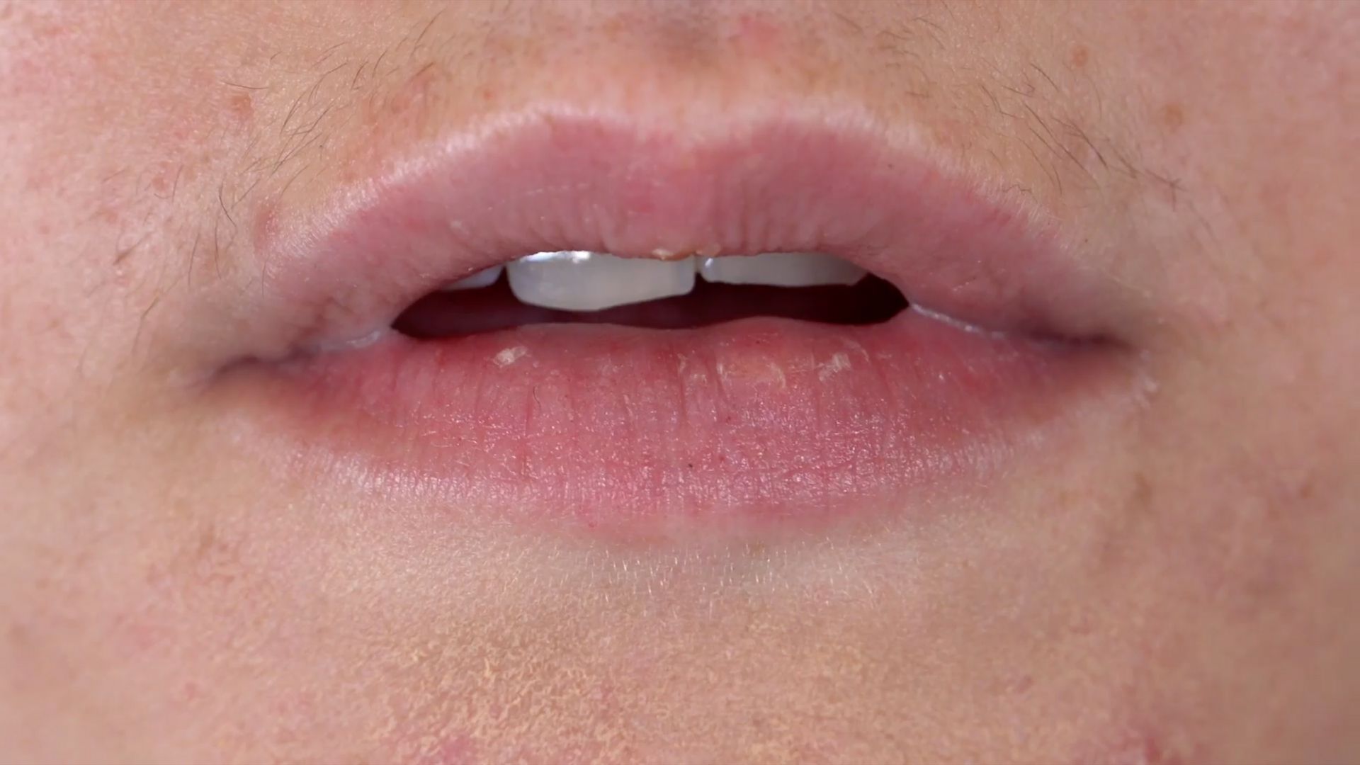 ultra close up image of a mouth, lips parted, teeth visible.