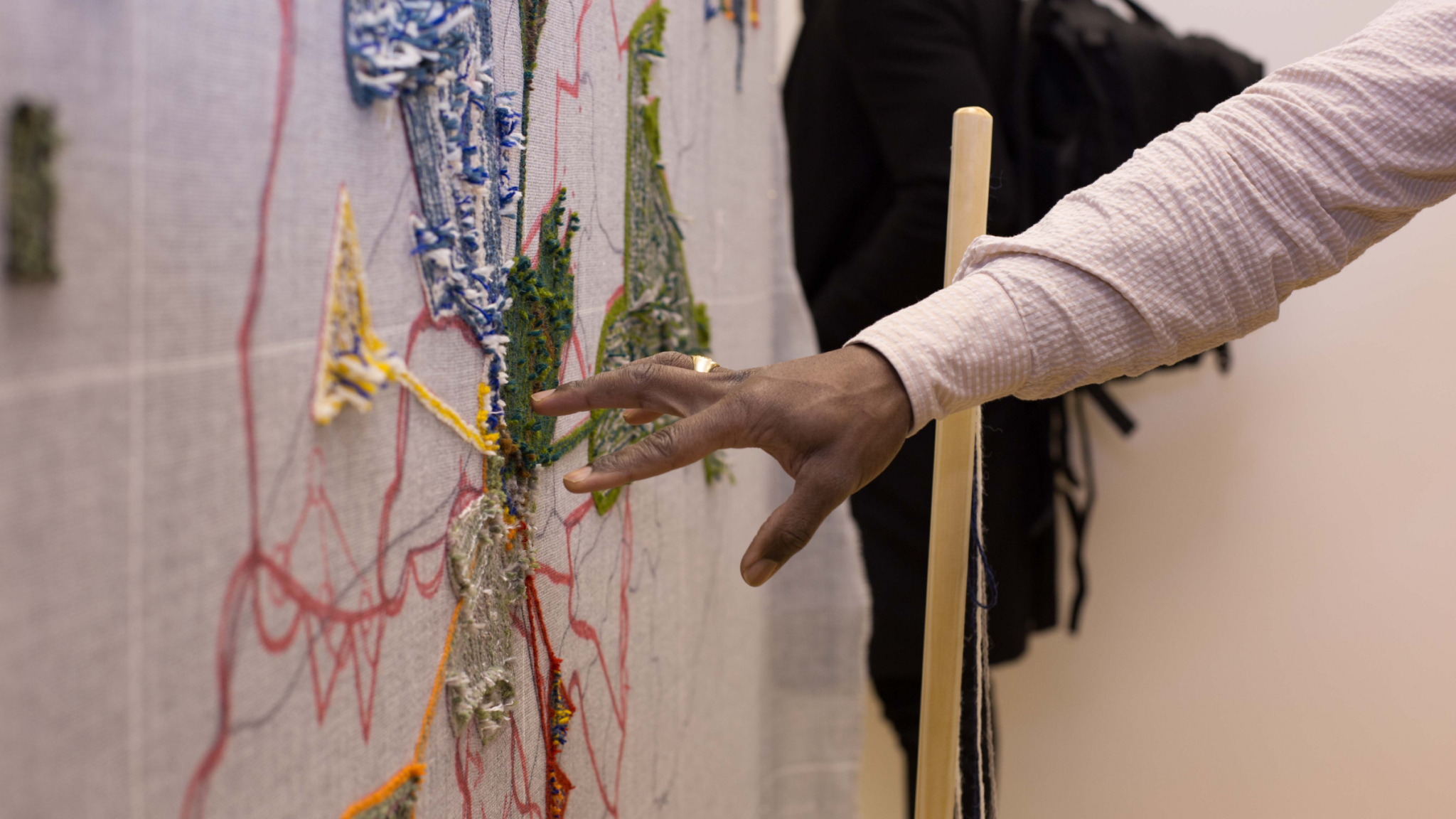 a photo of Benaiah with one of his tapestries in a gallery