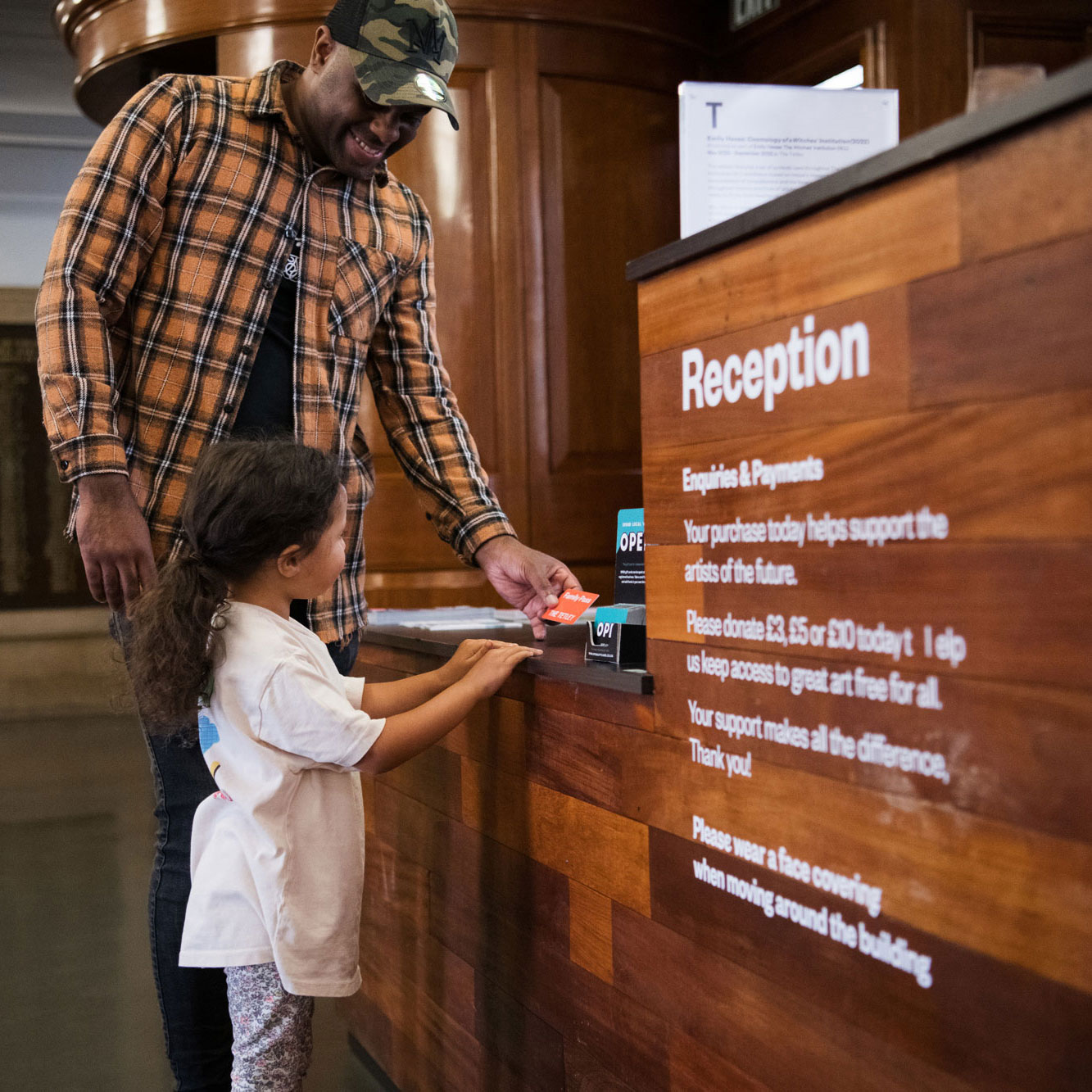 A dad and his daughter sign in at Reception at The Tetley with their free Family Pass