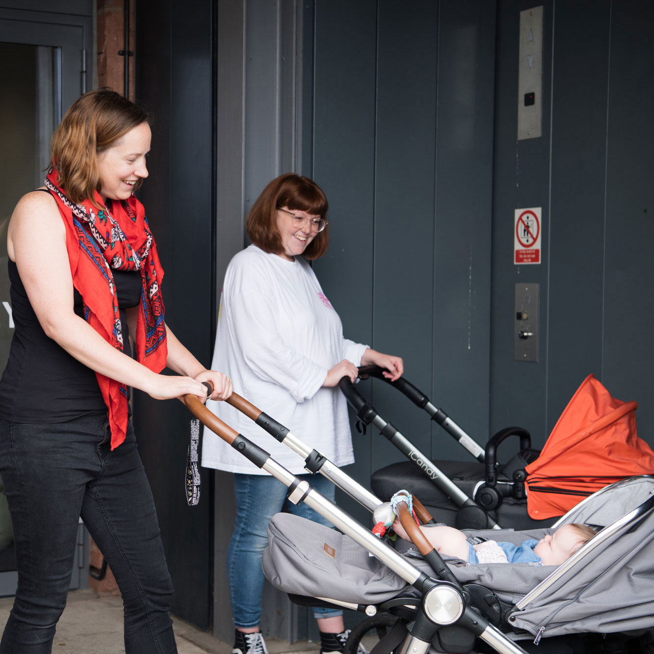 Two mums with prams head to The Tetley's lift at the back of the building