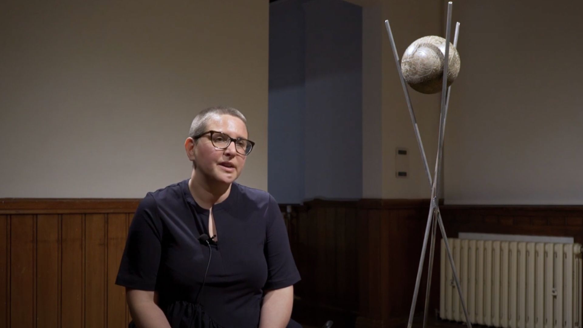 A still of Emily Hesse sat next to a Visioning Ball in Gallery 7