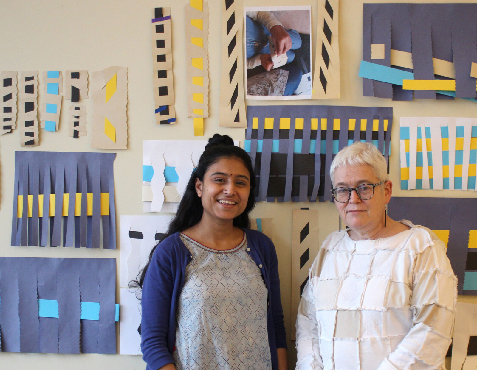 Two people stood in front of paper weaving