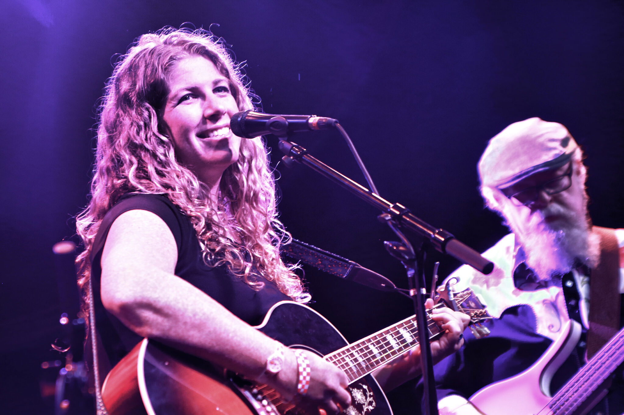 Purple lighting on a woman and man playing guitars