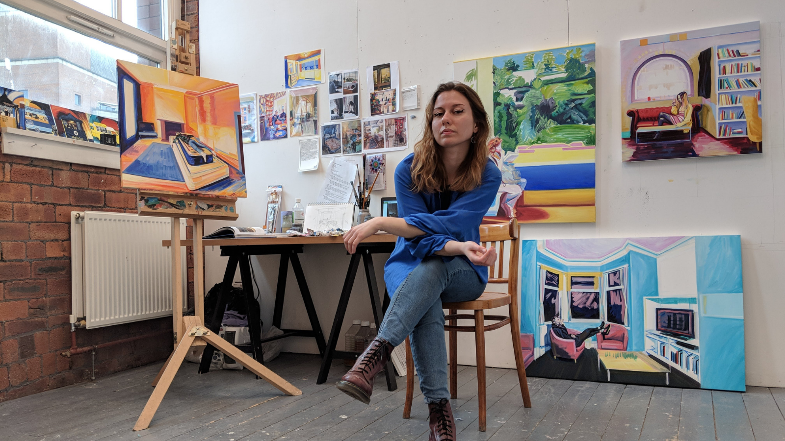 Artist Julia Pomeroy sat in her studio surrounded by brightly coloured paintings