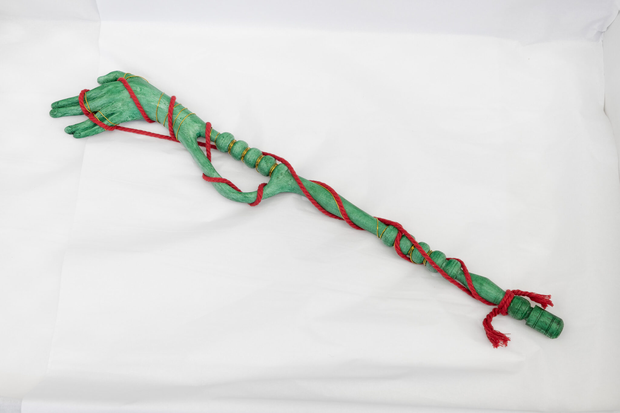 an image of Justin Fitzpatrick's Artist Edition 'Vegetal Hand' made of green painted urethane, red macramé cord and brass wire.
