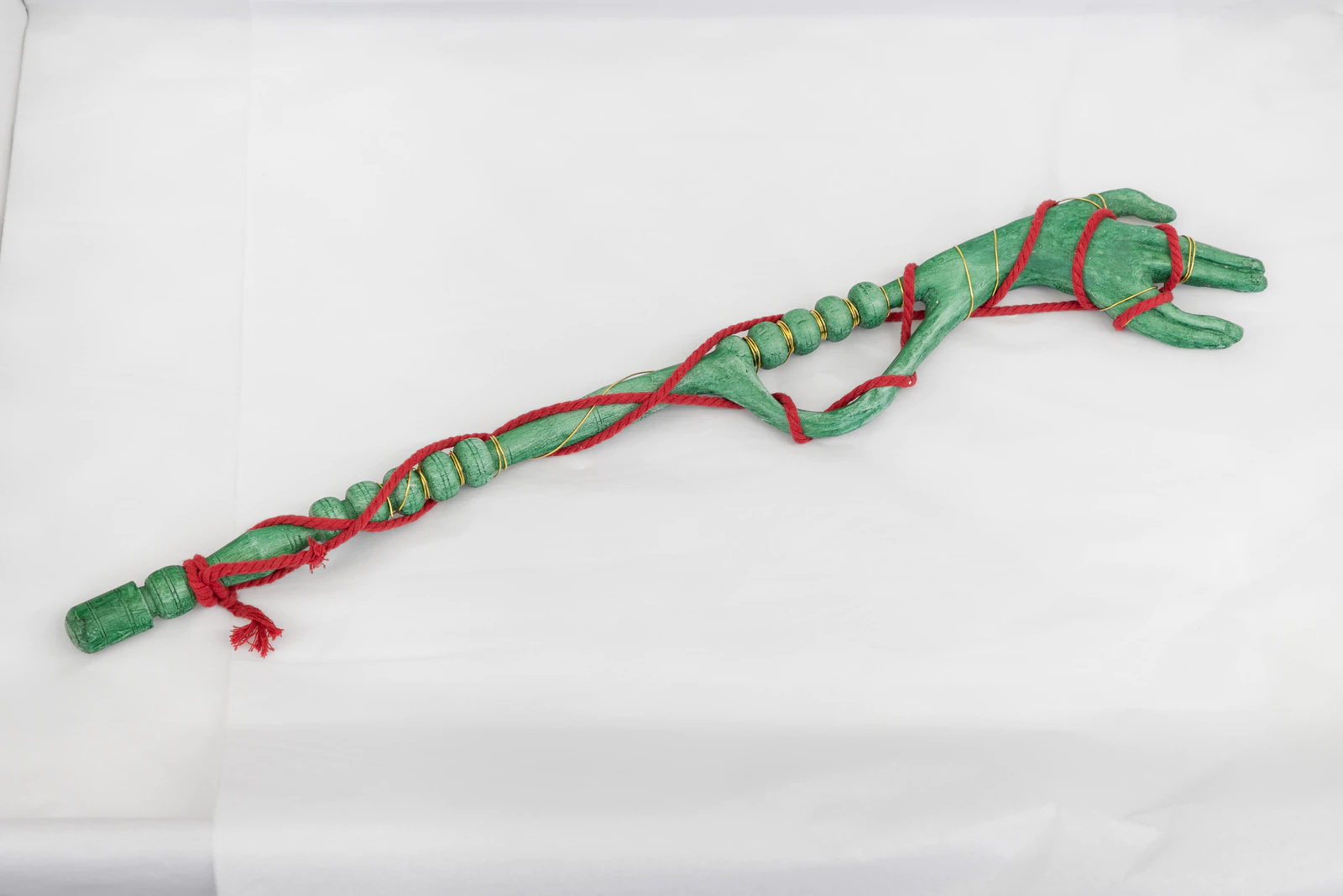 an image of Justin Fitzpatrick's Artist Edition 'Vegetal Hand' made of green painted urethane, red macramé cord and brass wire.