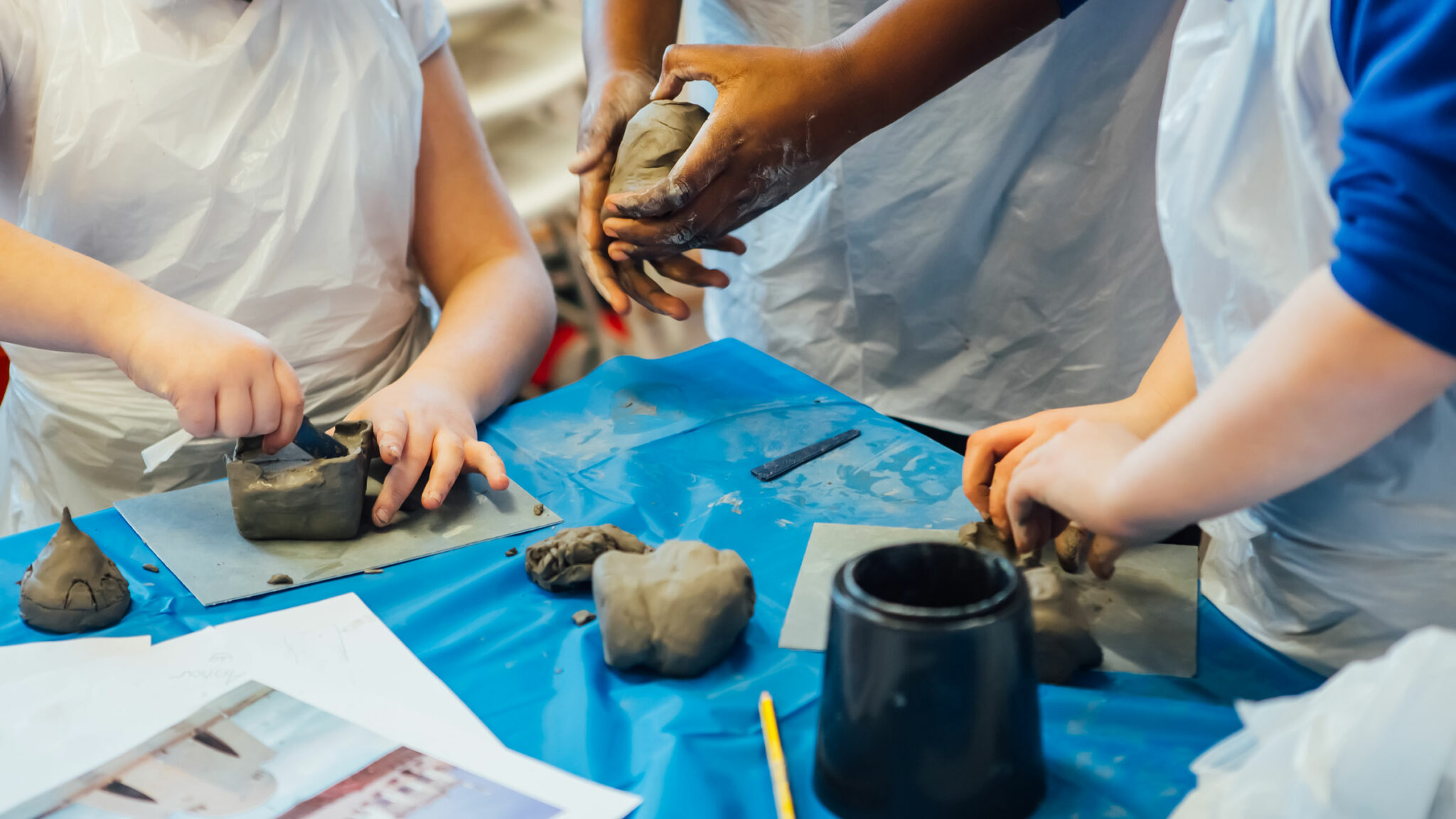Children wearing school uniform shape clay