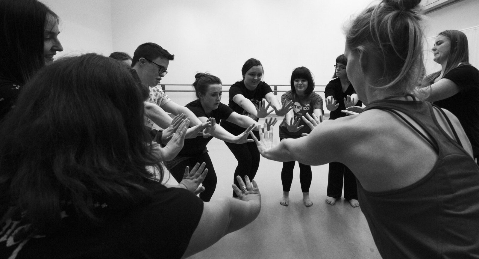 A black and white photo of people holding their hands together in a studio