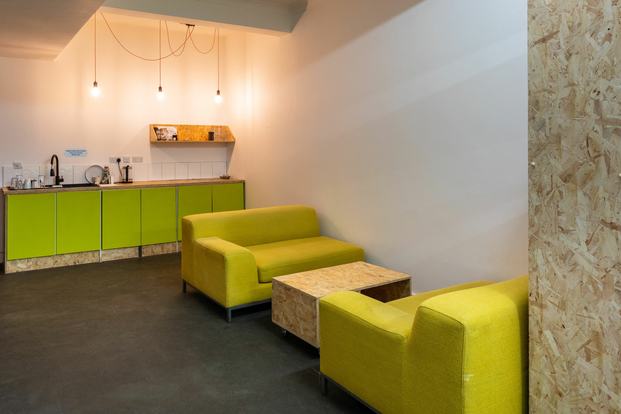 The back of the room with yellow sofas and hanging pendant lights