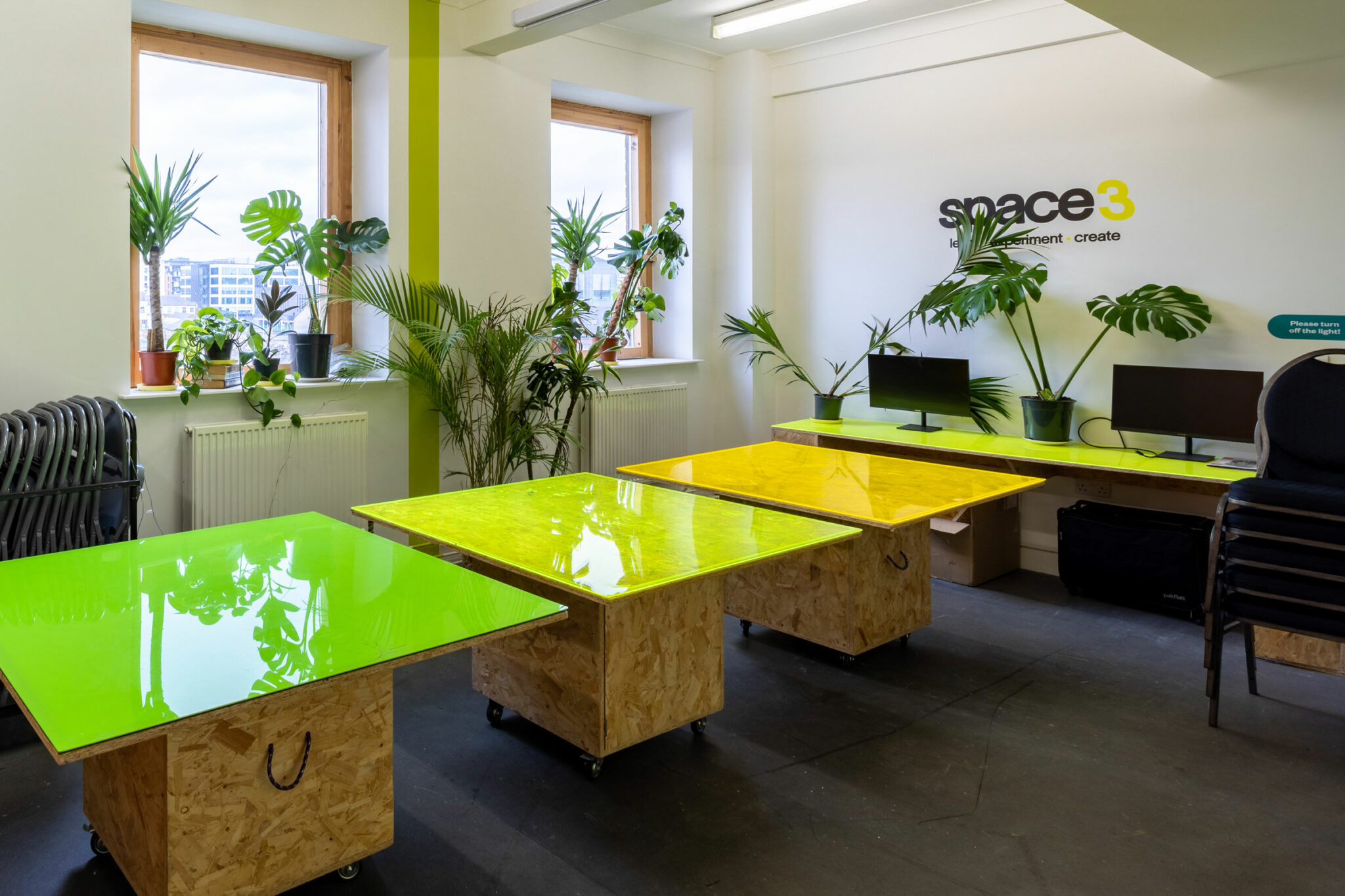 Three tables with neon tops and plants in the background