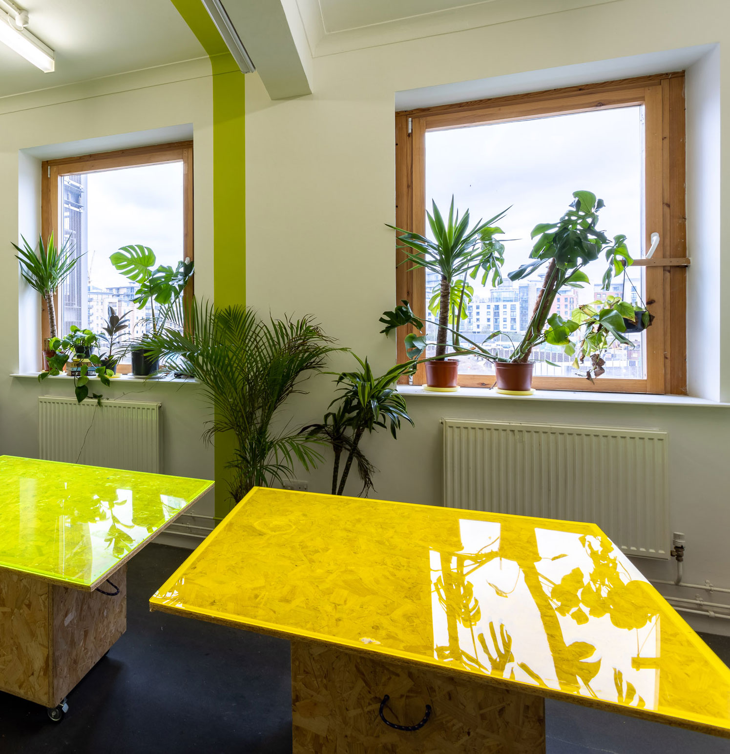 A room with tables with neon tops and lots of plants