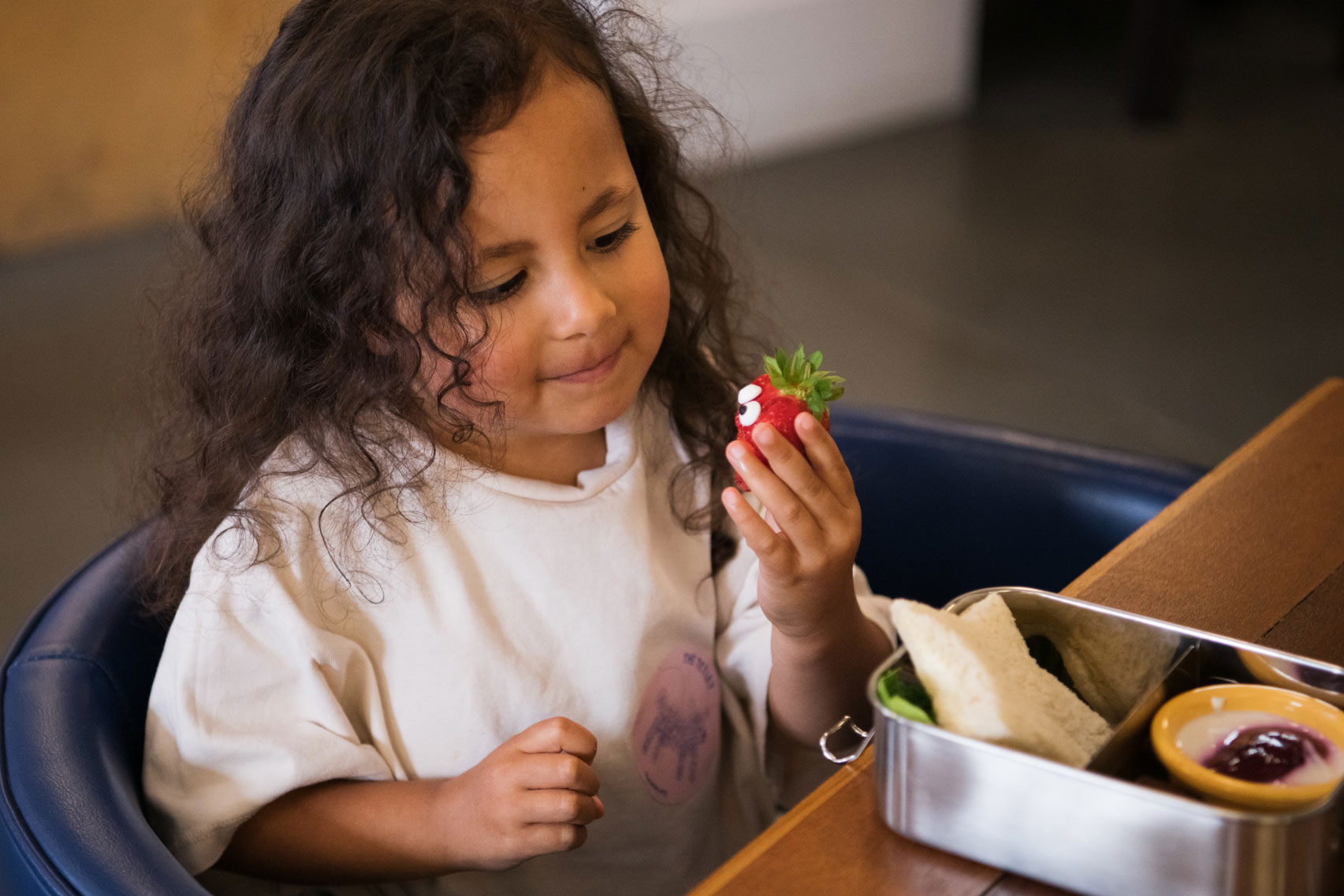 A child looks at a piece of fruit from her kids' Bento Box from The Tetley Bar & Kitchen menu