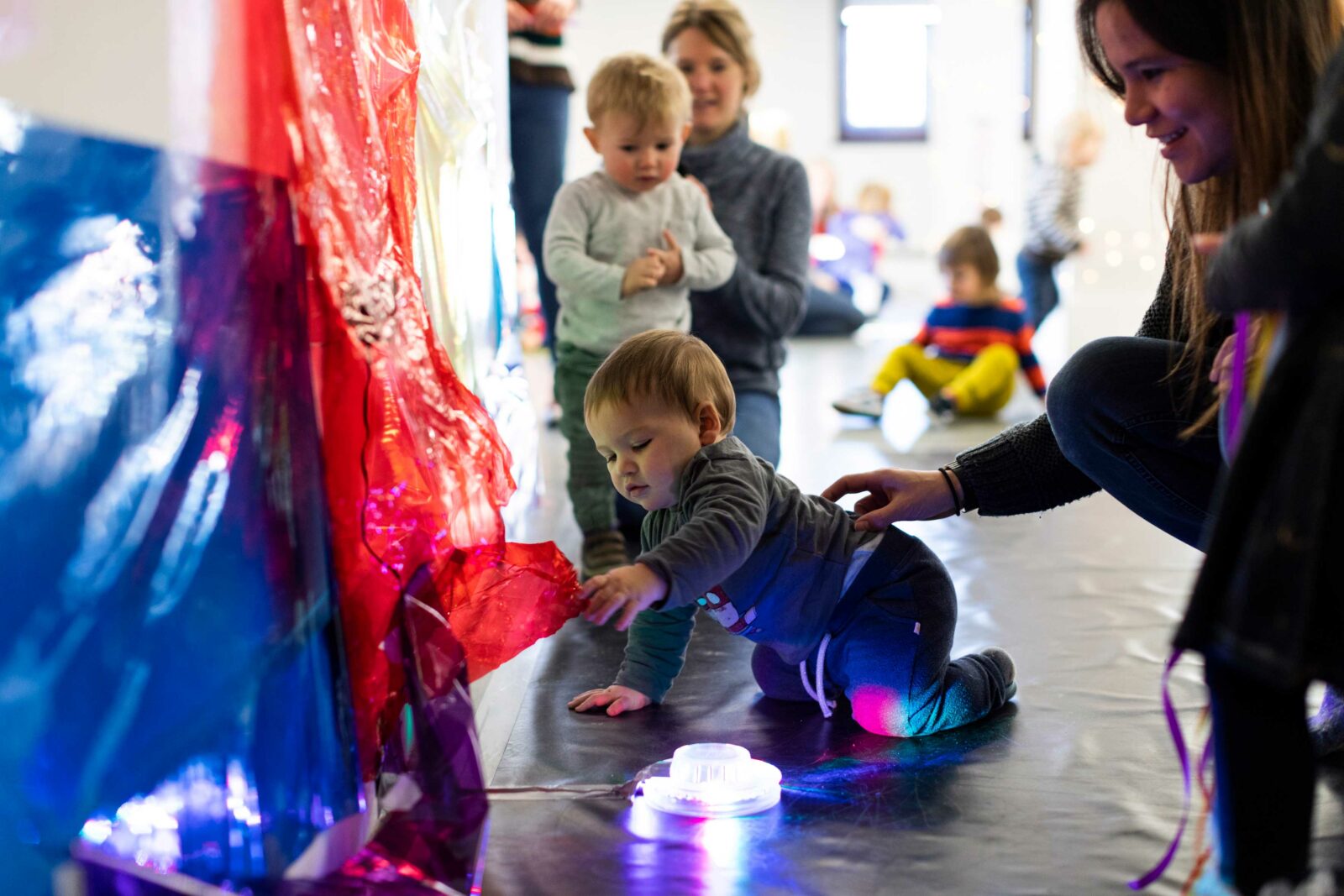 A baby in a gallery plays with fabric