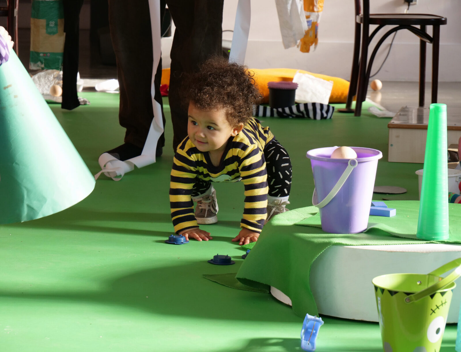 Toddler crouches in a brightly coloured room