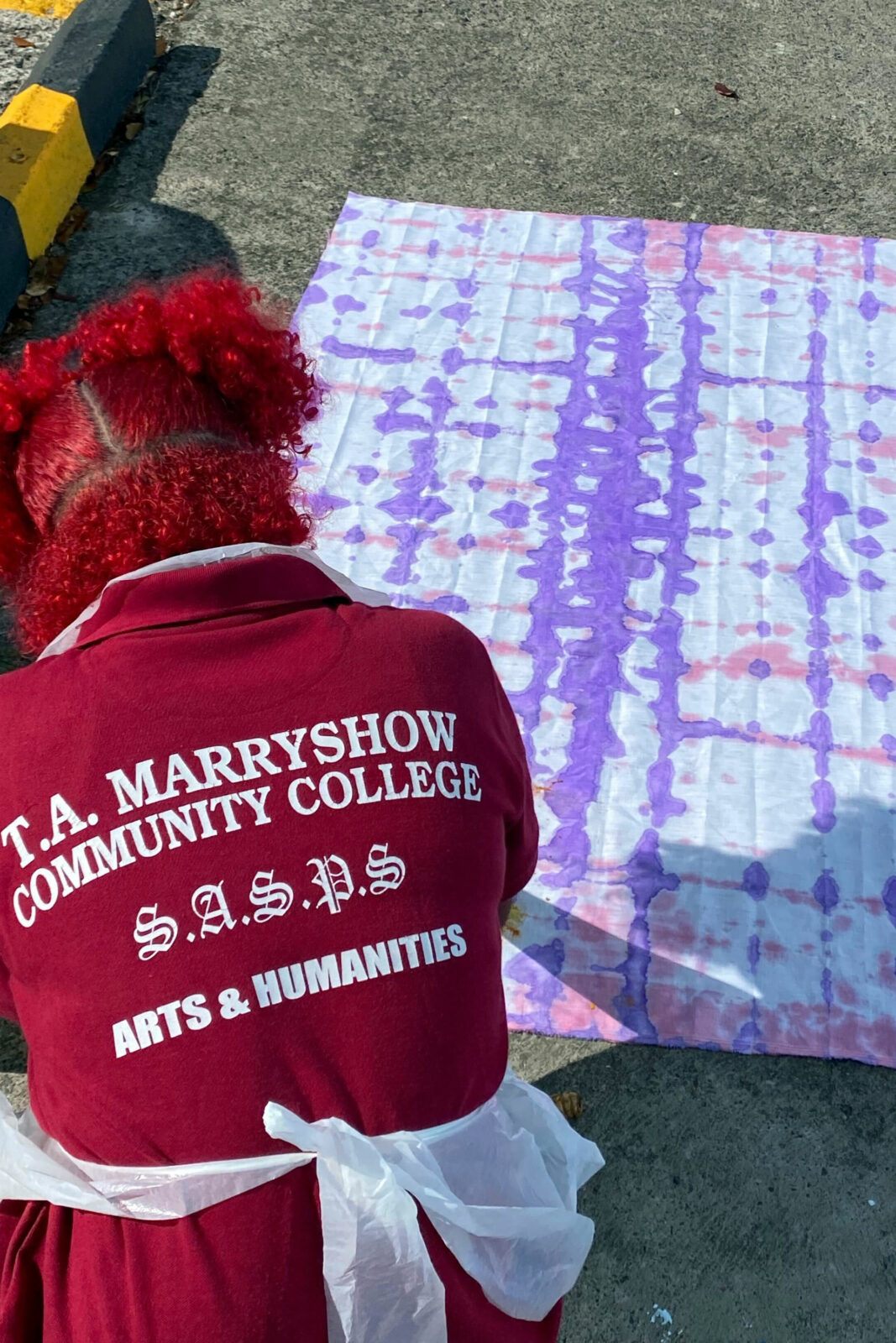 A student leans over a large pink and purple patterned flag