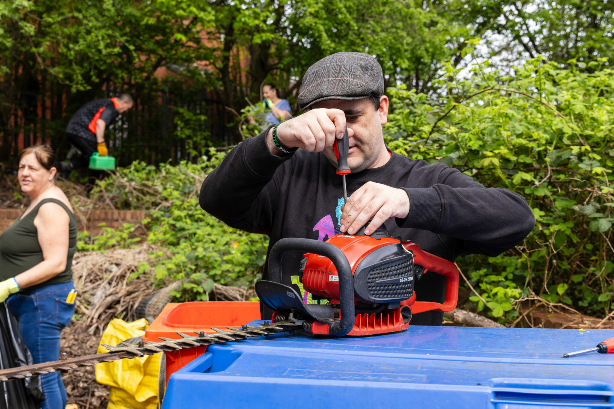 People outside with tools clearing a scrubby area
