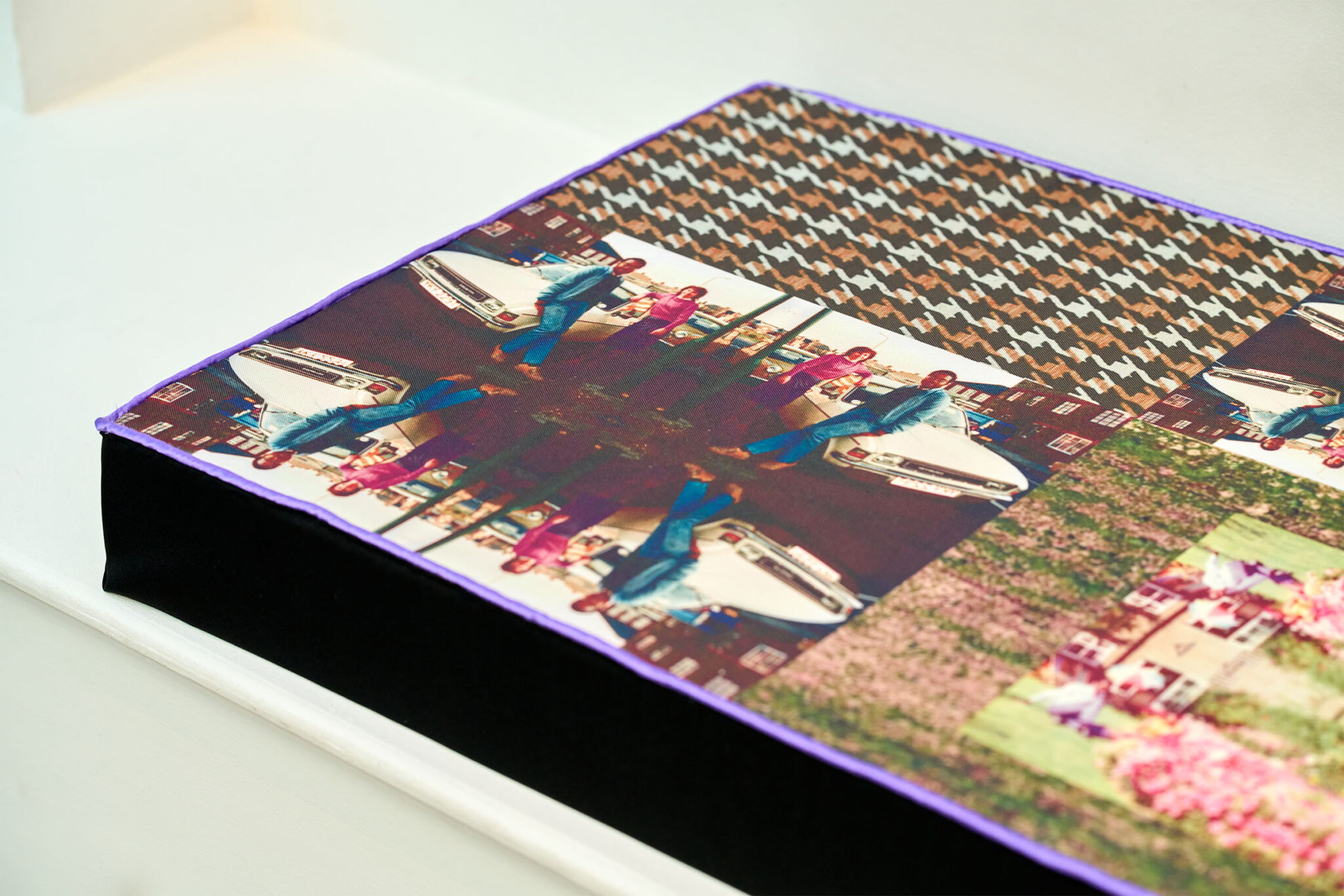 Close-up of a textile-covered bench edged in purple, featuring a collage of repeated photographs, patterned fabric and floral imagery.