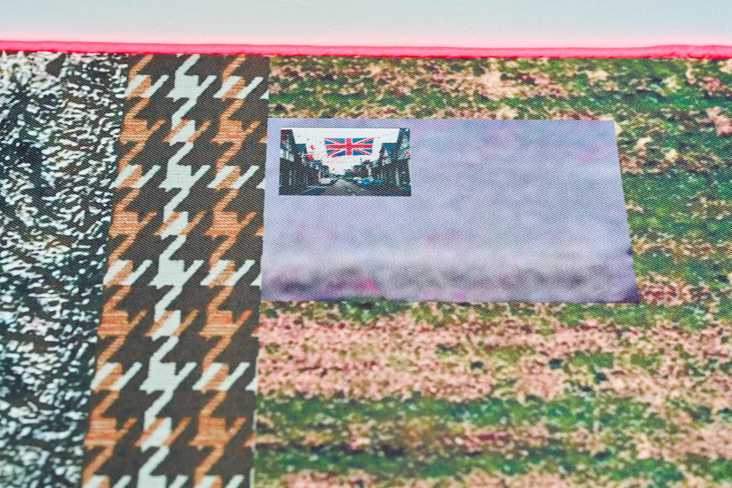 Close-up of a textile-covered bench featuring layered photographic and patterned imagery, including flowers, abstract motifs and a small street scene with Union Jack flags.